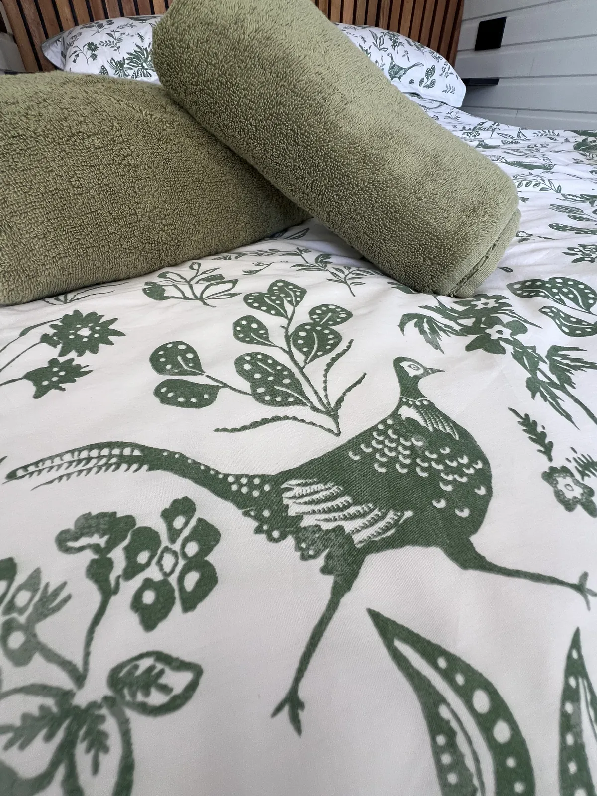 Bed linen and rolled green towels