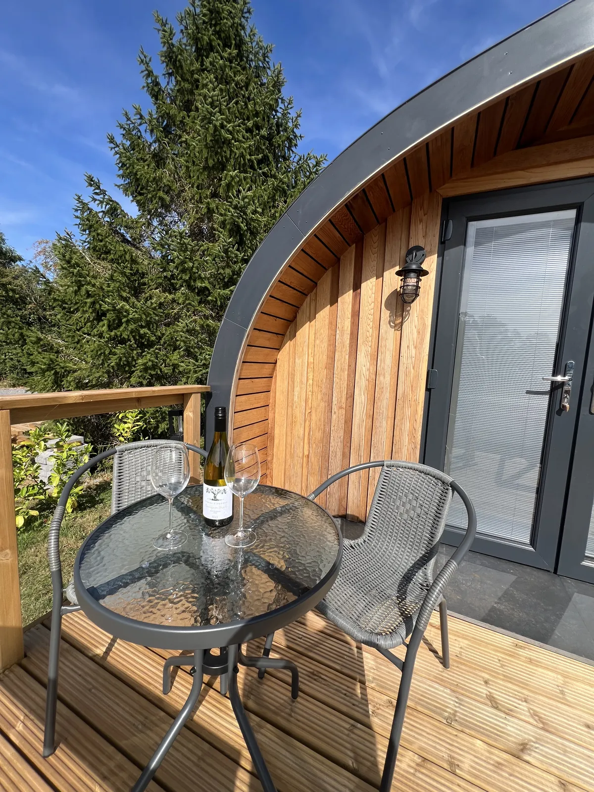Table on the decking set with a bottle of wine and two glasses